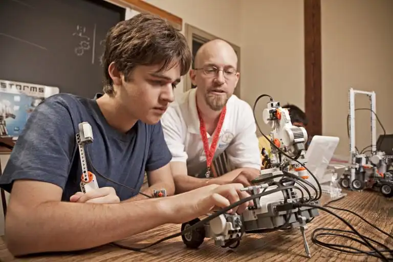 A camper works with a counselor on a robotics and engineering project