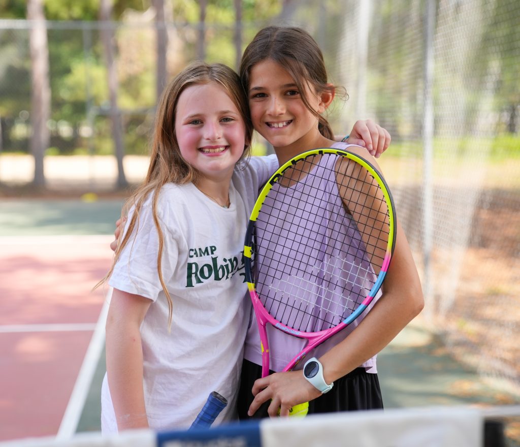 smiling girls at summer camp playing tennis
