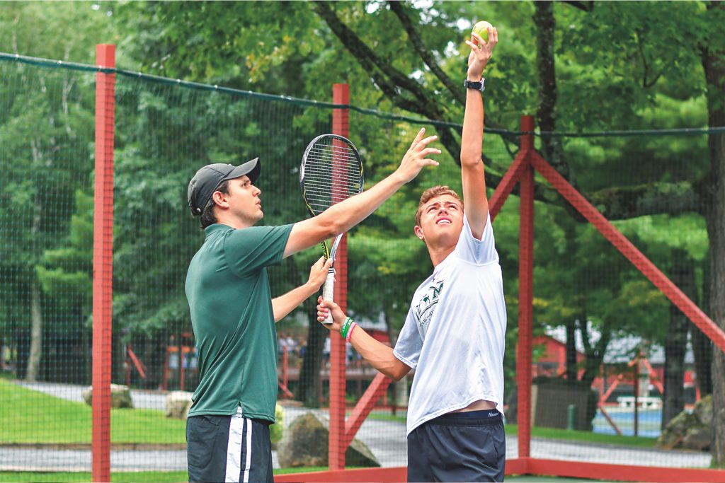 summer camp coach teaches tennis