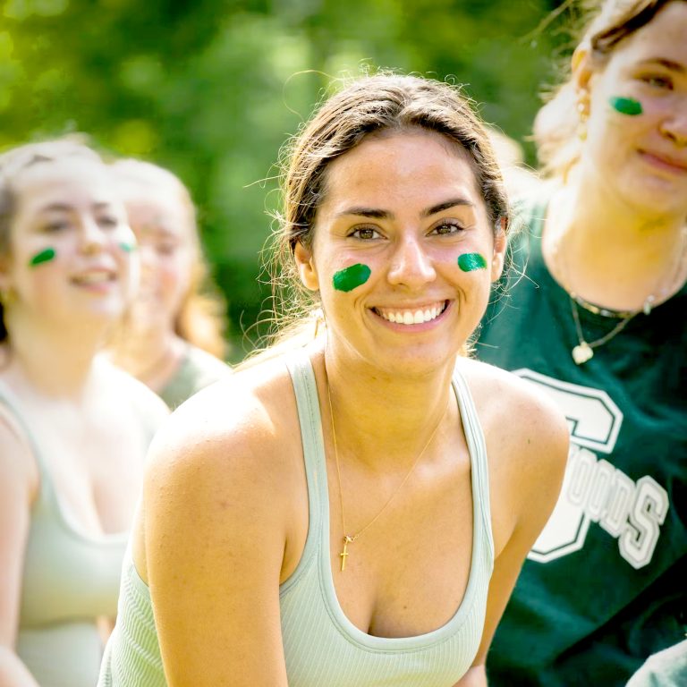 A smiling camp staff member with festive face paint, ready for a camp job